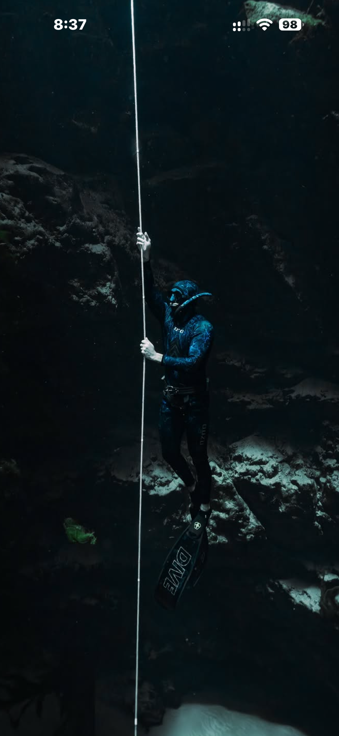 Adam freediving underwater alongside a descent line