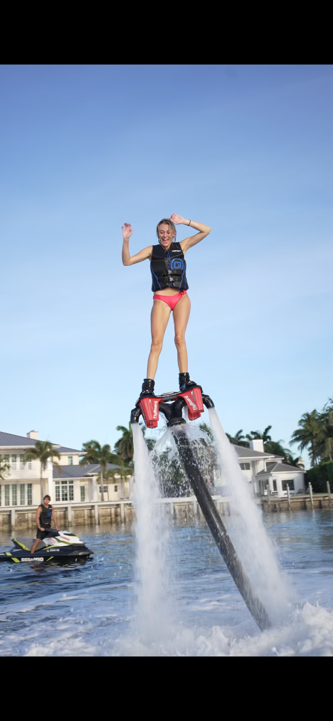 Guest flying above the water on a flyboard powered by two water jets
